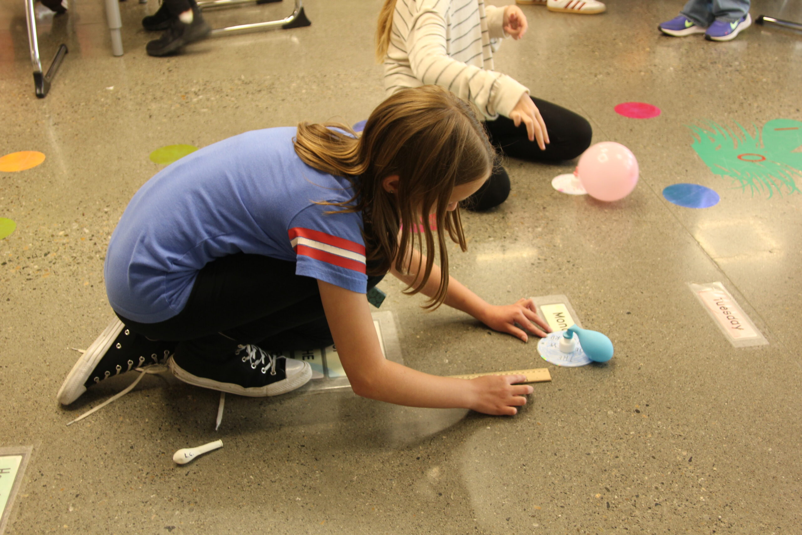 Student measures distance traveled by balloon powered hovercraft