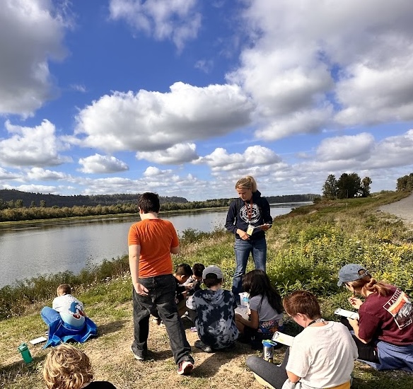 Teacher and students journal during field trip with Columbia River in background