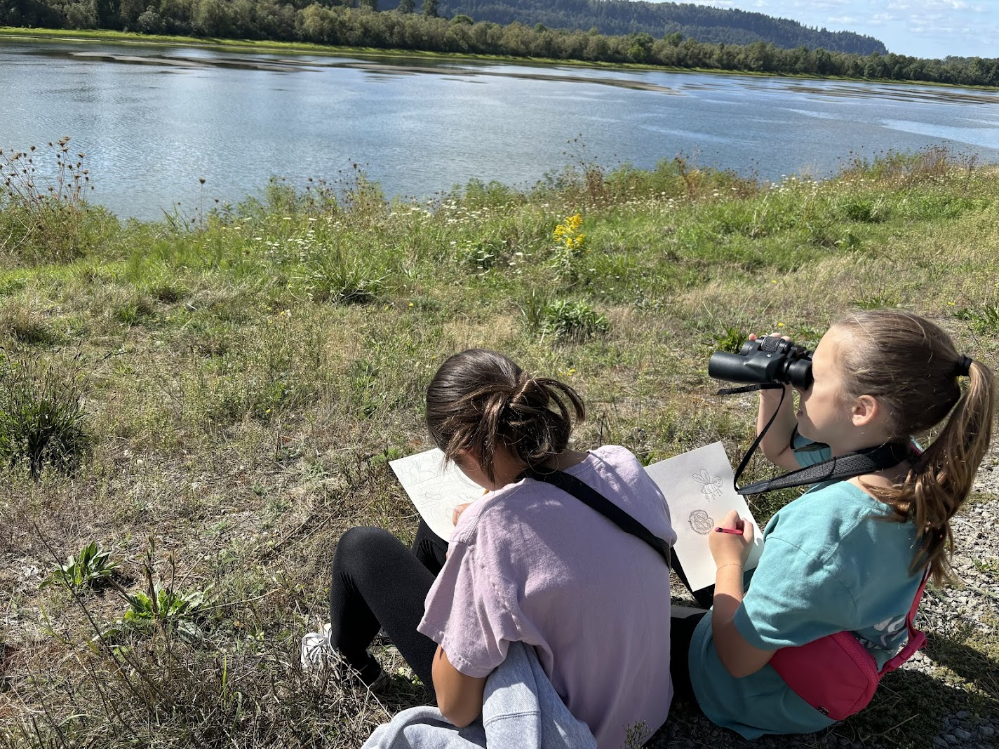 Students use binoculars to spot native birds and journal during field trip with Steigerwald Lake in background