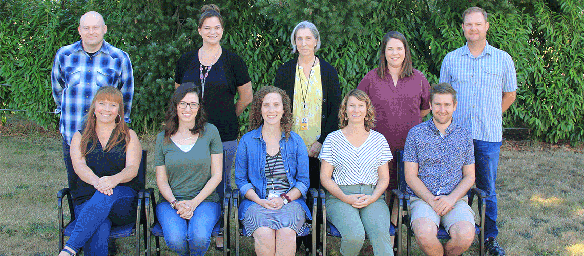 New teachers to the Washougal School district, with 10 teachers, half standing half sitting in front of some bushes