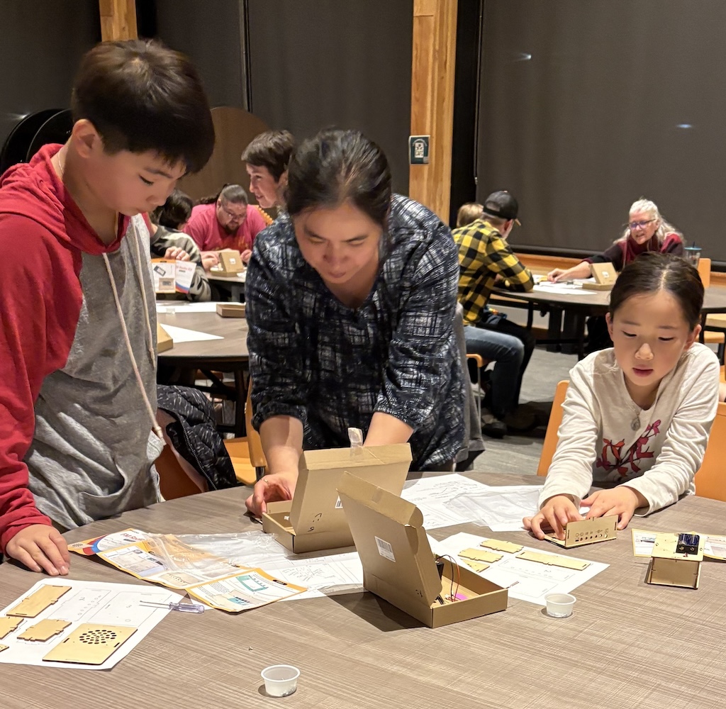 Students and parent assemble radio kit at table 